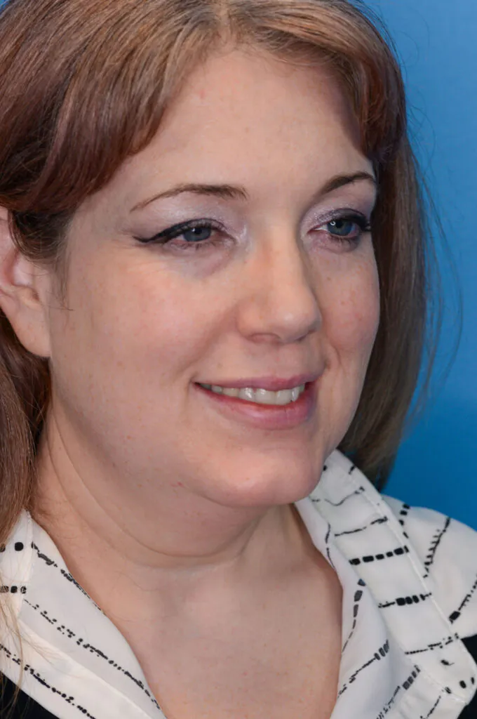 A woman smiles in front of a blue background.