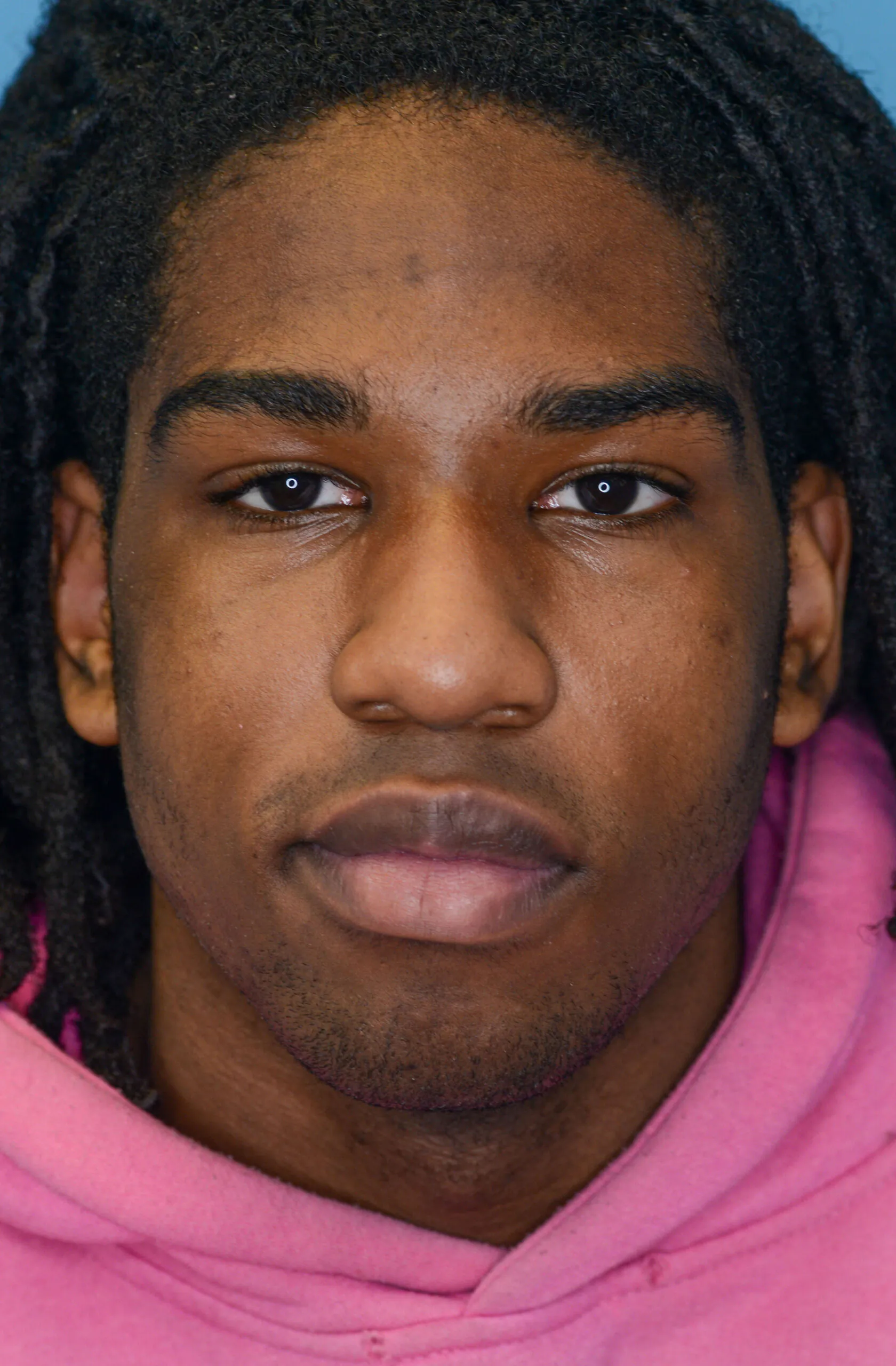 Young person wearing a pink hoodie in a close-up portrait.